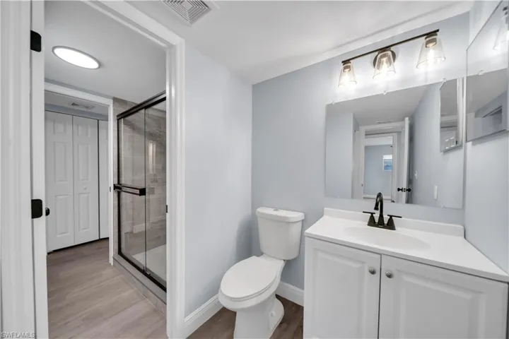 Bathroom featuring a white vanity with integrated sink, matte black faucet, and a wall-mounted mirror with a three-light fixture