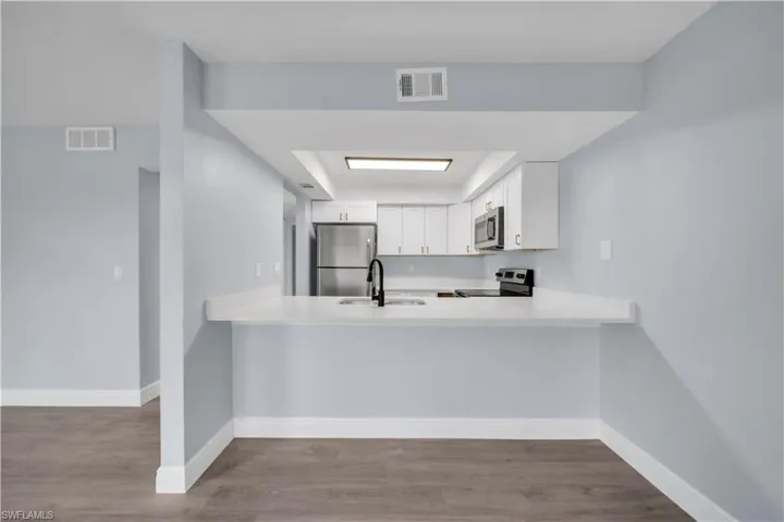 Kitchen passthrough with white countertops and a black gooseneck faucet