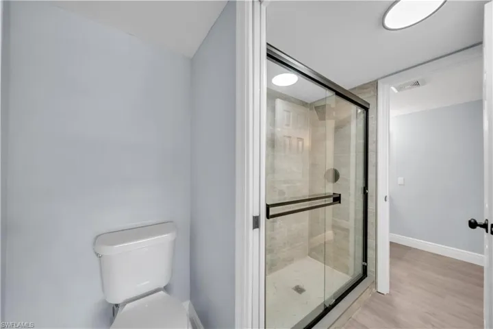Modern full bathroom featuring a glass-enclosed shower with tile surround, a white toilet, and contemporary overhead lighting