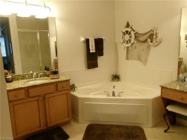 Full bath featuring a bath, tile patterned flooring, a shower stall, and vanity