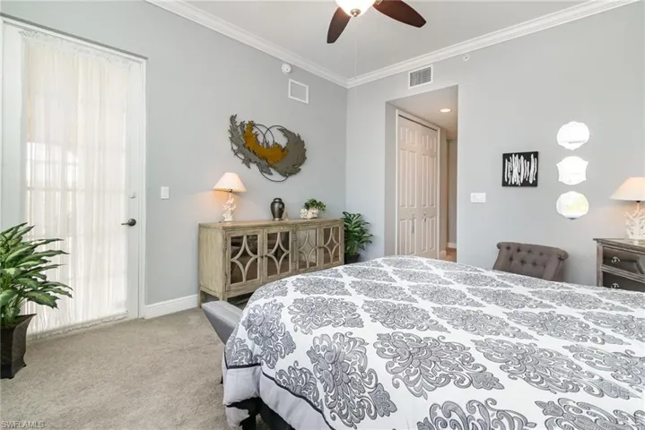 Carpeted bedroom with baseboards, a ceiling fan, visible vents, and crown molding