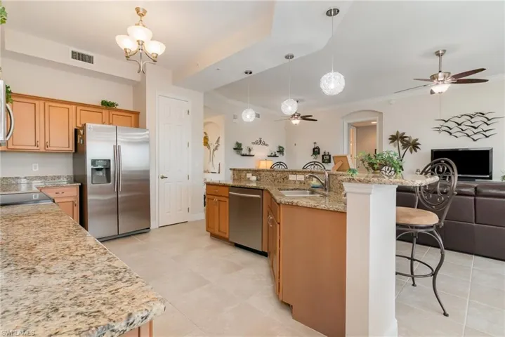 Kitchen featuring ceiling fan with notable chandelier, open floor plan, stainless steel appliances, and a sink