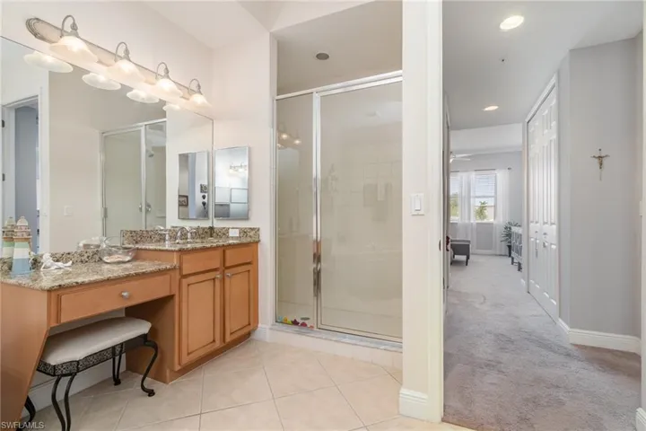 Ensuite bathroom with a shower stall, tile patterned flooring, vanity, ensuite bath, and baseboards