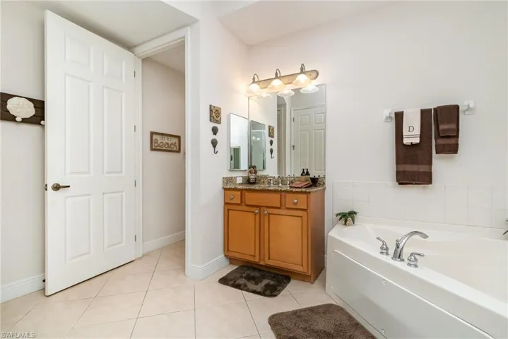 Full bathroom featuring a bath, tile patterned floors, baseboards, and vanity