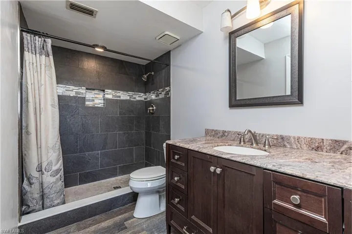 Bathroom featuring vanity, a shower stall, and dark wood-type flooring