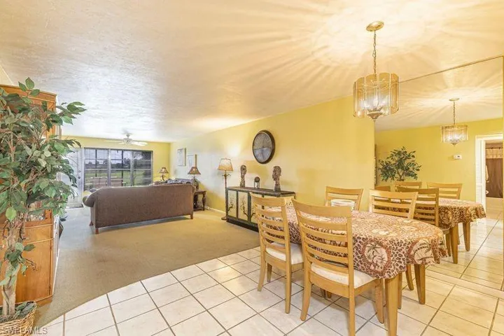 Dining area with light colored carpet, light tile patterned floors, and a ceiling fan