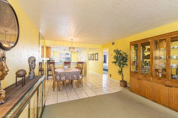 Dining area with light tile patterned floors, a textured ceiling, light colored carpet, and suspended lighting