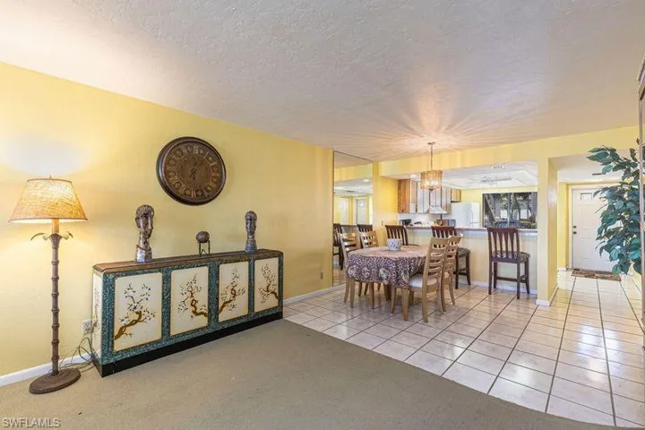 Dining space featuring a textured ceiling, light colored carpet, light tile patterned floors, and suspended lighting