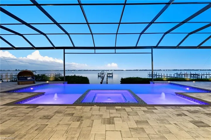View of swimming pool with glass enclosure, a water view, and a pool with connected hot tub