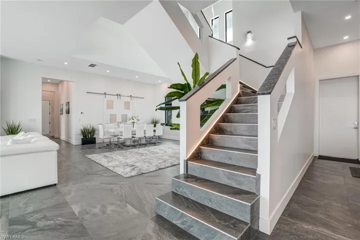 Staircase with a barn door, recessed lighting, a high ceiling, and marble tiled flooring
