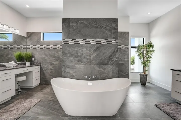 Full bath with vanity, a soaking tub, tile walls, and recessed lighting