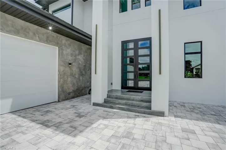 Property entrance featuring french doors, stucco siding, a garage, and a patio area