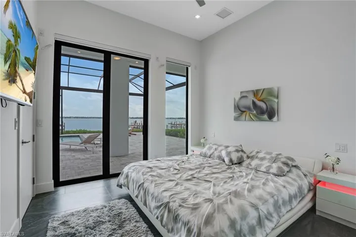 Tiled bedroom with a water view, access to outside, a ceiling fan, and recessed lighting