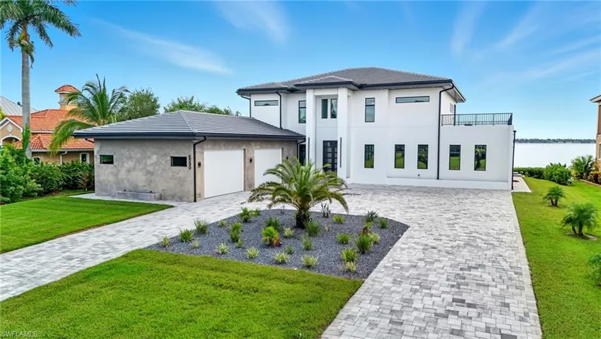 View of front facade with a front lawn, decorative driveway, stucco siding, and an attached garage