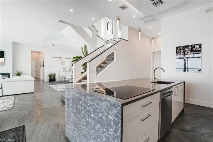 Kitchen featuring modern cabinets, a barn door, dark stone counters, pendant lighting, and a high ceiling
