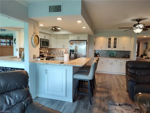 Kitchen featuring appliances with stainless steel finishes, white cabinets, ceiling fan, and backsplash