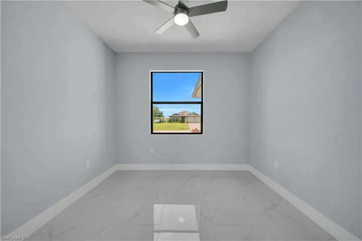 Well-lit interior space featuring neutral wall tones, large format tile flooring, a modern ceiling fan, and a double-pane window