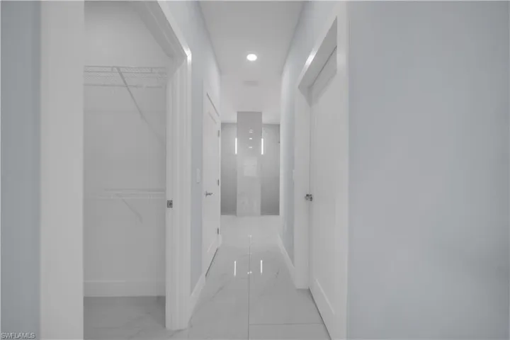 Clean-lined hallway featuring recessed lighting, a closet with wire shelving, and light-toned tile flooring