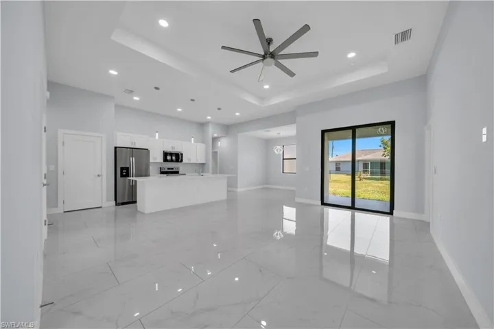 Open concept interior featuring large format tile flooring, a contemporary ceiling fan, and recessed lighting