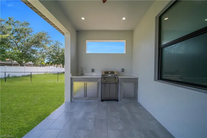 Covered patio featuring a built-in outdoor kitchen with a grill, sink, and stainless steel cabinetry
