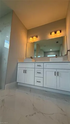 Full bathroom featuring light marble finish floors and double vanity