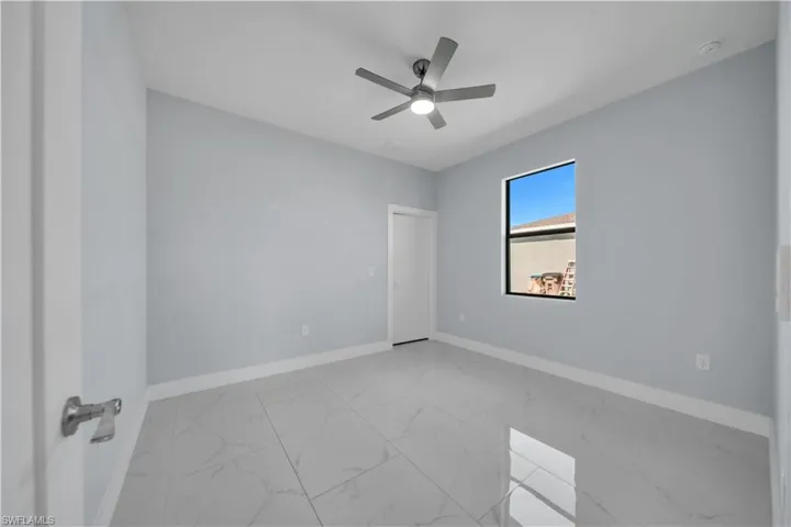 Spacious room featuring light blue walls, large format tile flooring, and a contemporary ceiling fan
