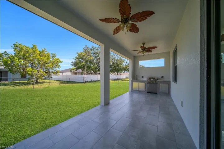 Covered patio featuring ceramic tile flooring and two ceiling fans