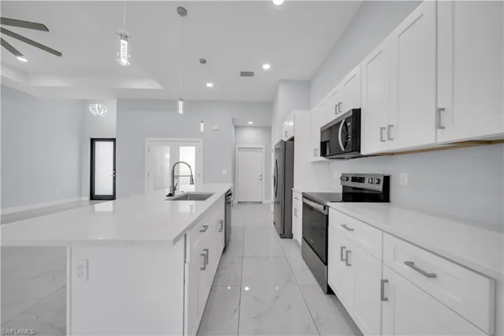Modern kitchen featuring white cabinetry, quartz countertops, and stainless steel appliances