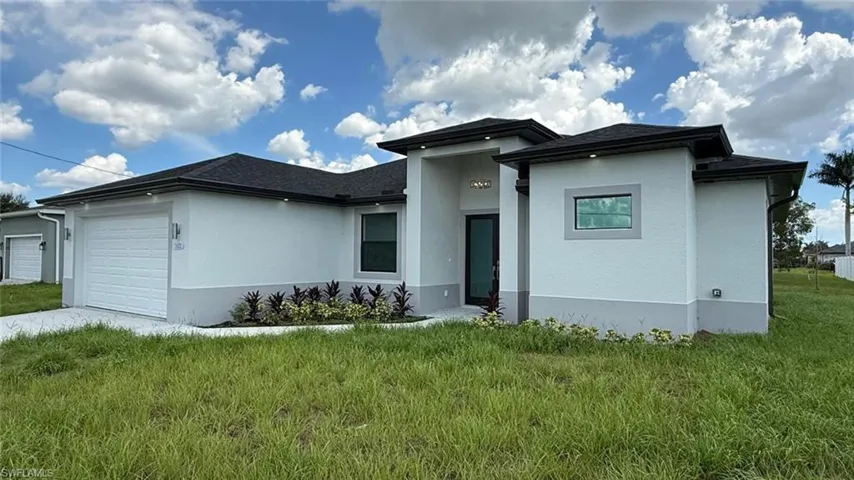 View of front of property with a garage, stucco siding, and a front lawn