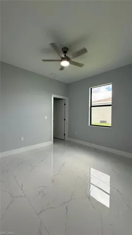 Unfurnished room featuring light marble finish floors and a ceiling fan
