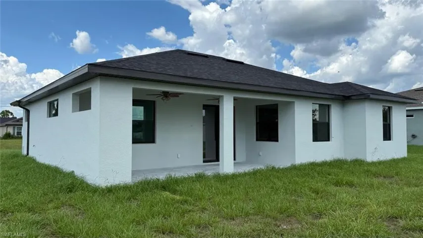 Back of property with a patio, a lawn, ceiling fan, stucco siding, and a shingled roof