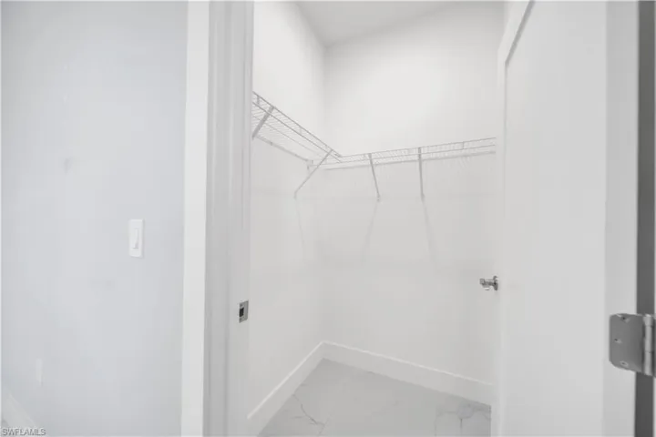 Dedicated closet space featuring wire shelving, white baseboards, and light-toned tile flooring