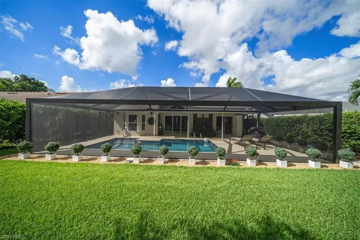 Back of property with a yard, glass enclosure, and a patio area