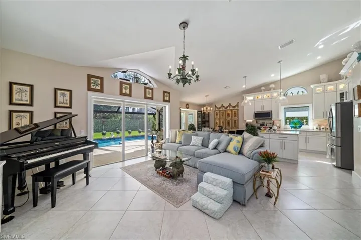 Tiled living room featuring high vaulted ceiling, an inviting chandelier, and a wealth of natural light