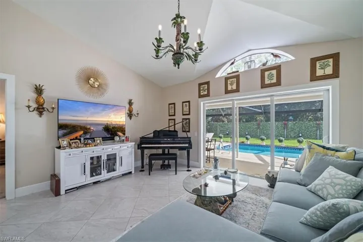Living room with a chandelier, high vaulted ceiling, and light tile floors