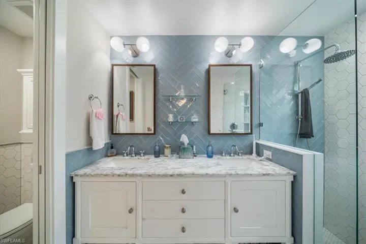 Bathroom featuring dual vanity, a shower with door, tasteful backsplash, and toilet