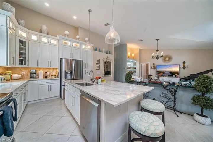 Kitchen with white cabinets, backsplash, hanging light fixtures, appliances with stainless steel finishes, and sink