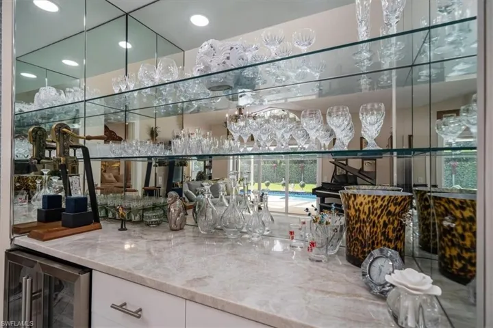 Bar featuring light stone counters, white cabinetry, and beverage cooler