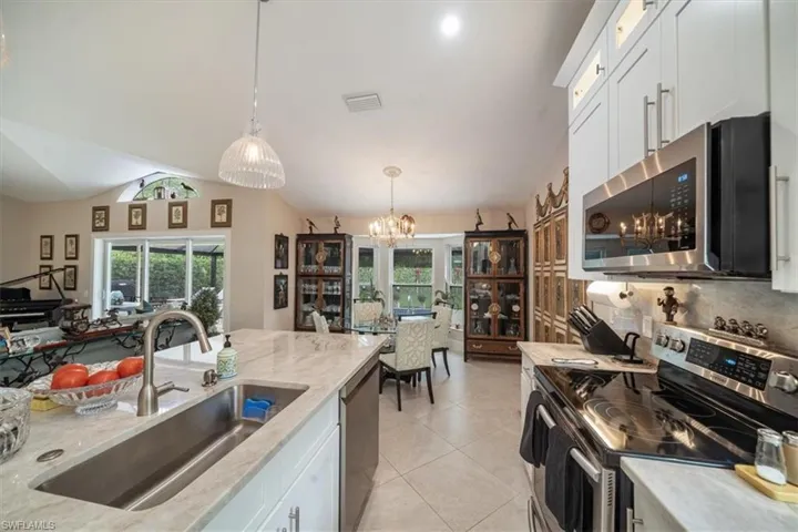 Kitchen featuring light tile flooring, pendant lighting, sink, white cabinets, and appliances with stainless steel finishes
