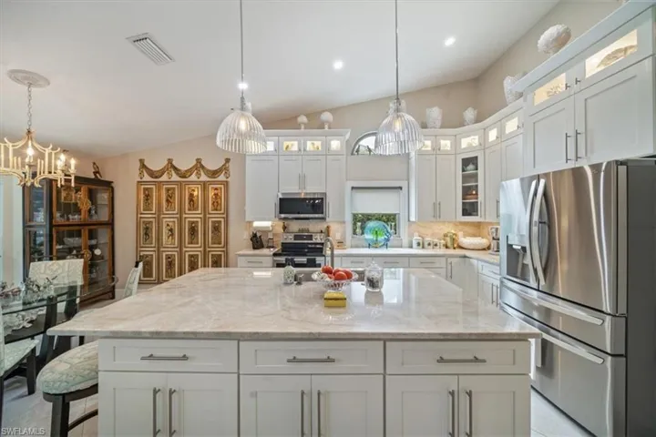 Kitchen featuring stainless steel appliances, a kitchen island, tasteful backsplash, and decorative light fixtures