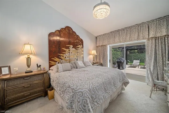 Bedroom featuring a chandelier, carpet flooring, vaulted ceiling, and access to exterior