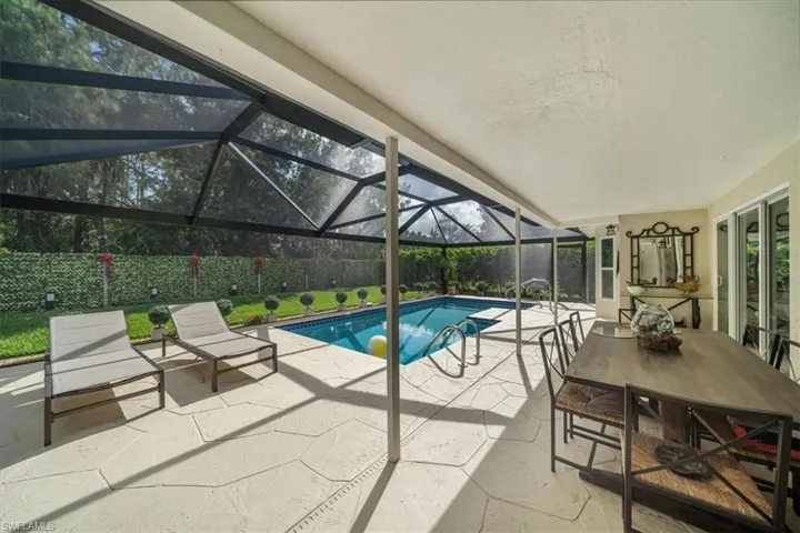 View of swimming pool with glass enclosure and a patio area