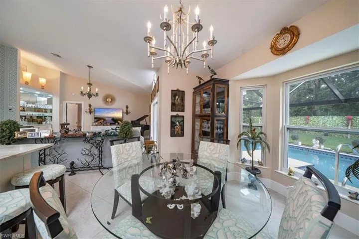 Dining room with lofted ceiling, light tile floors, and an inviting chandelier