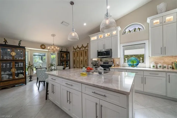 Kitchen featuring tasteful backsplash, vaulted ceiling, decorative light fixtures, a center island, and appliances with stainless steel finishes