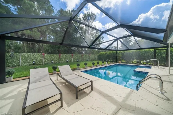 View of pool with glass enclosure and a patio