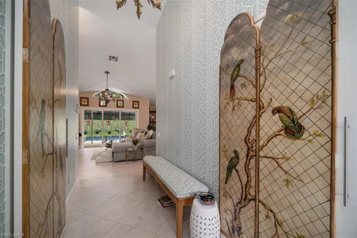 Hall with tile flooring and lofted ceiling