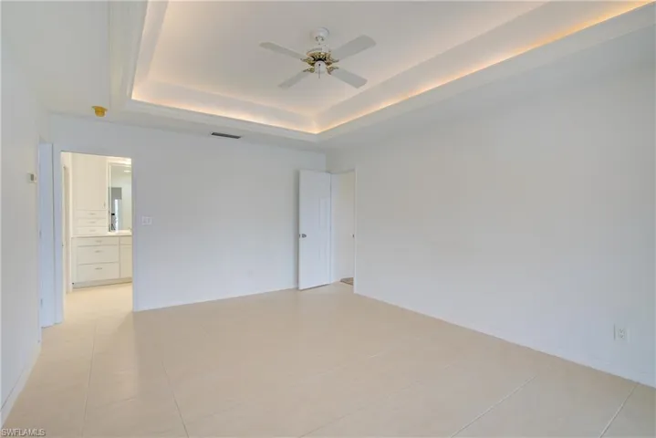 Tiled spare room with ceiling fan and a raised ceiling