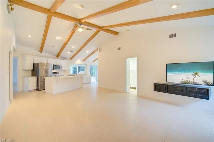 Unfurnished living room featuring high vaulted ceiling, beam ceiling, ceiling fan, and light tile patterned flooring