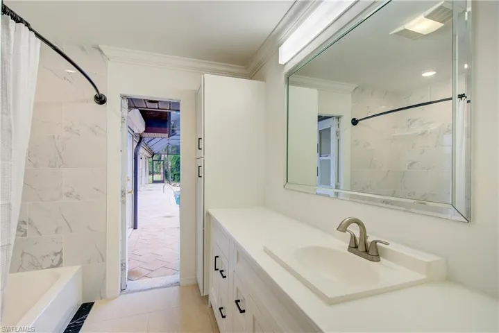 Bathroom featuring vanity, shower / bath combination with curtain, tile patterned floors, and ornamental molding