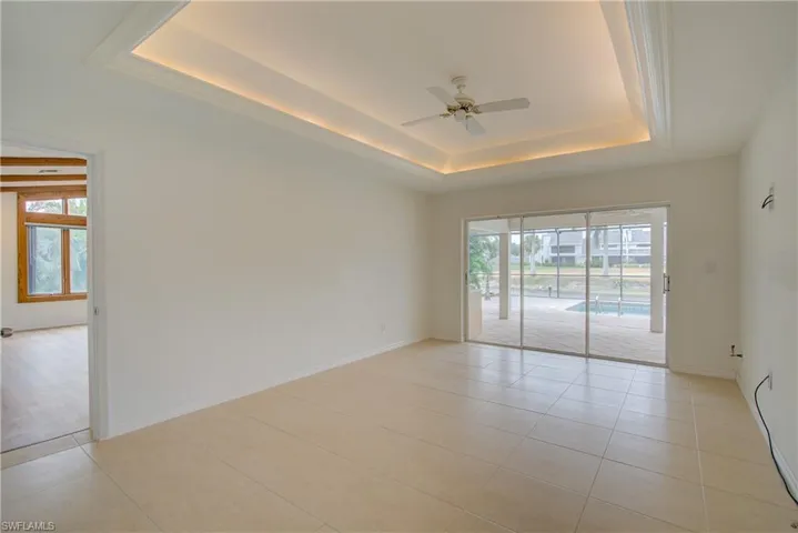 Tiled empty room with a raised ceiling and ceiling fan